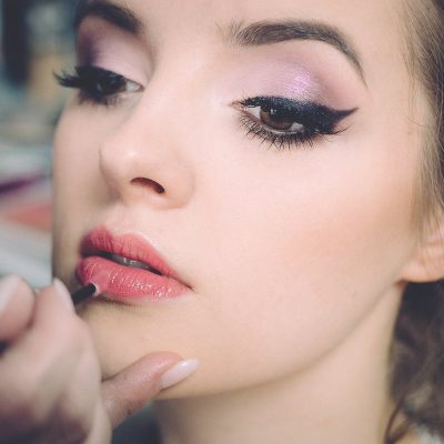 Kadının göz kapağında pembe simli far, uçlu siyah eyeliner ve rimelli kirpikleri yakından görünüyor